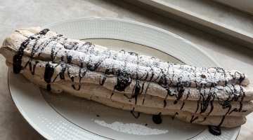 en bild på en budapest rulle bakelse på ett vitt fat med guldkanter som sitter på diskbänken 